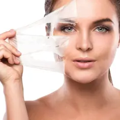 Kobieta zdejmuje maskę, odsłaniając gładką skórę. To efekt działania peelingu chemicznego.