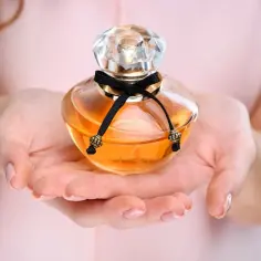 Eleganckie currara perfumy damskie w szklanej buteleczce z kryształowym korkiem, ozdobione czarną wstążką.