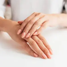 Dłonie z idealnym, jasnoróżowym manicure. Chcesz wiedzieć, jak zapuścić paznokcie w tydzień?