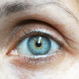 Zbliżenie na niebieskie oko z naturalnie wyglądającymi rzęsami.