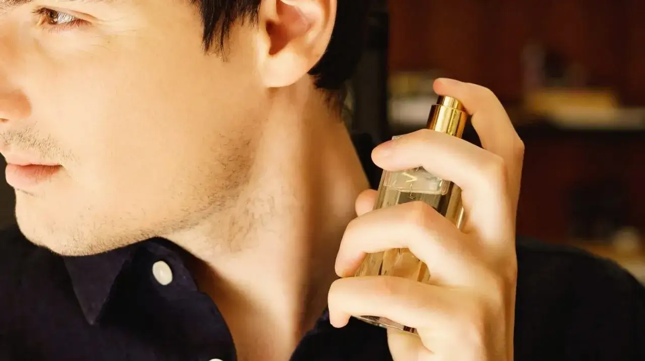 Mężczyzna aplikuje perfumy na szyję, pokazując, gdzie psikać perfumy, by zapach utrzymał się dłużej.