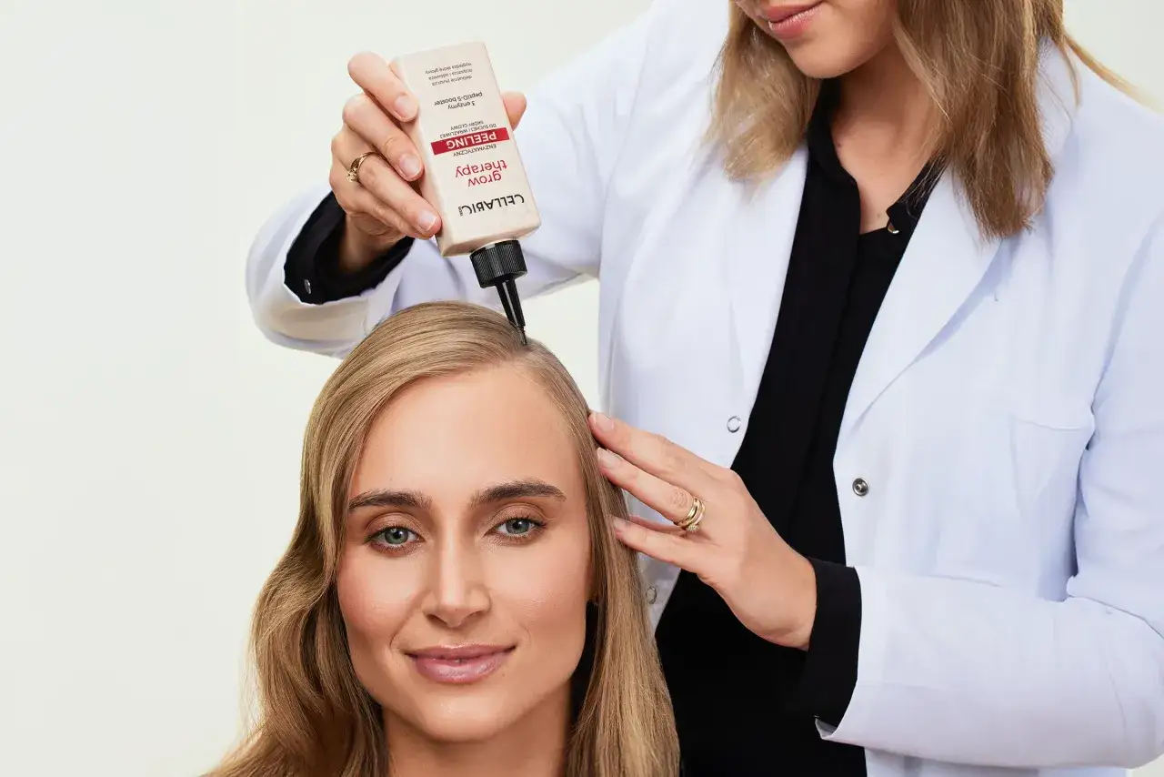 Kobieta w białym kitlu aplikuje enzymatyczny peeling do włosów na skórę głowy.