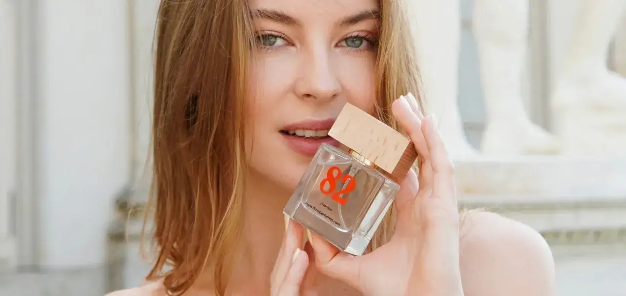 Kobieta trzyma perfumy, zastanawiając się, gdzie psikać perfumy, by zapach był subtelny i długotrwały.