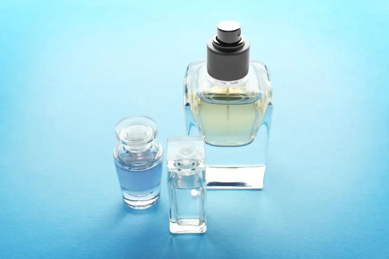 Trzy flakoniki perfum na niebieskim tle. Zastanawiasz się, edp co to? To woda perfumowana, jeden z rodzajów zapachów.